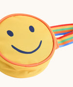 A close up of the front of the Frugi yellow happy smiley face children's rainbow coloured belt bag. 