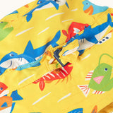Close up of the adjustable toggle on the front of the Frugi yellow adjustable swim hat with fish and shark sealife design.