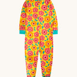 Frugi zelah zip up all in one with a floral fields print design. A bright yellow organic cotton all in one with pink and orange flowers all over with turquoise coloured arm and leg cuffs and collar trim.