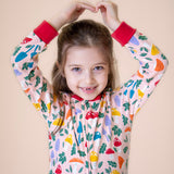 A close up of a child wearing the Frugi Zelah fun guys all in one zip suit available at Babipur showing the fund woodland print and full length zip detail