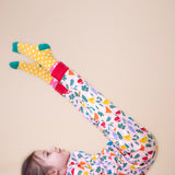 A child lying on the floor and wearing the Frugi Zelah fun guys all in one zip suit available at Babipur.