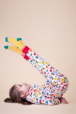 A child lying on the floor and wearing the Frugi Zelah fun guys all in one zip suit available at Babipur.