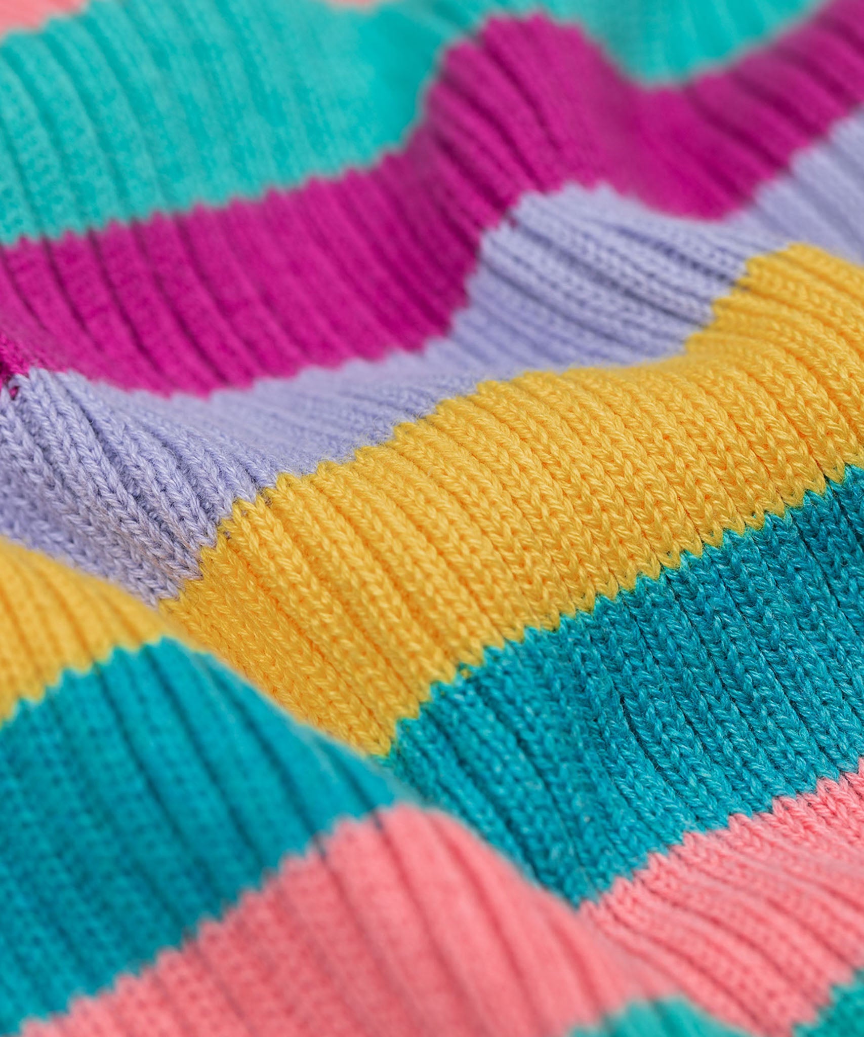 A close up of the material of the Frugi Zoe knitted jumper wild rainbow stripe top. This child's top is made with organic cotton.