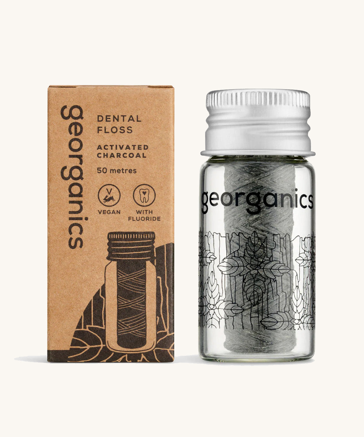 Georganics Charcoal Dental Floss with fluoride in a glass jar, next to cardboard packaging. 