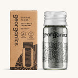Georganics Charcoal Dental Floss with fluoride in a glass jar, next to cardboard packaging. 