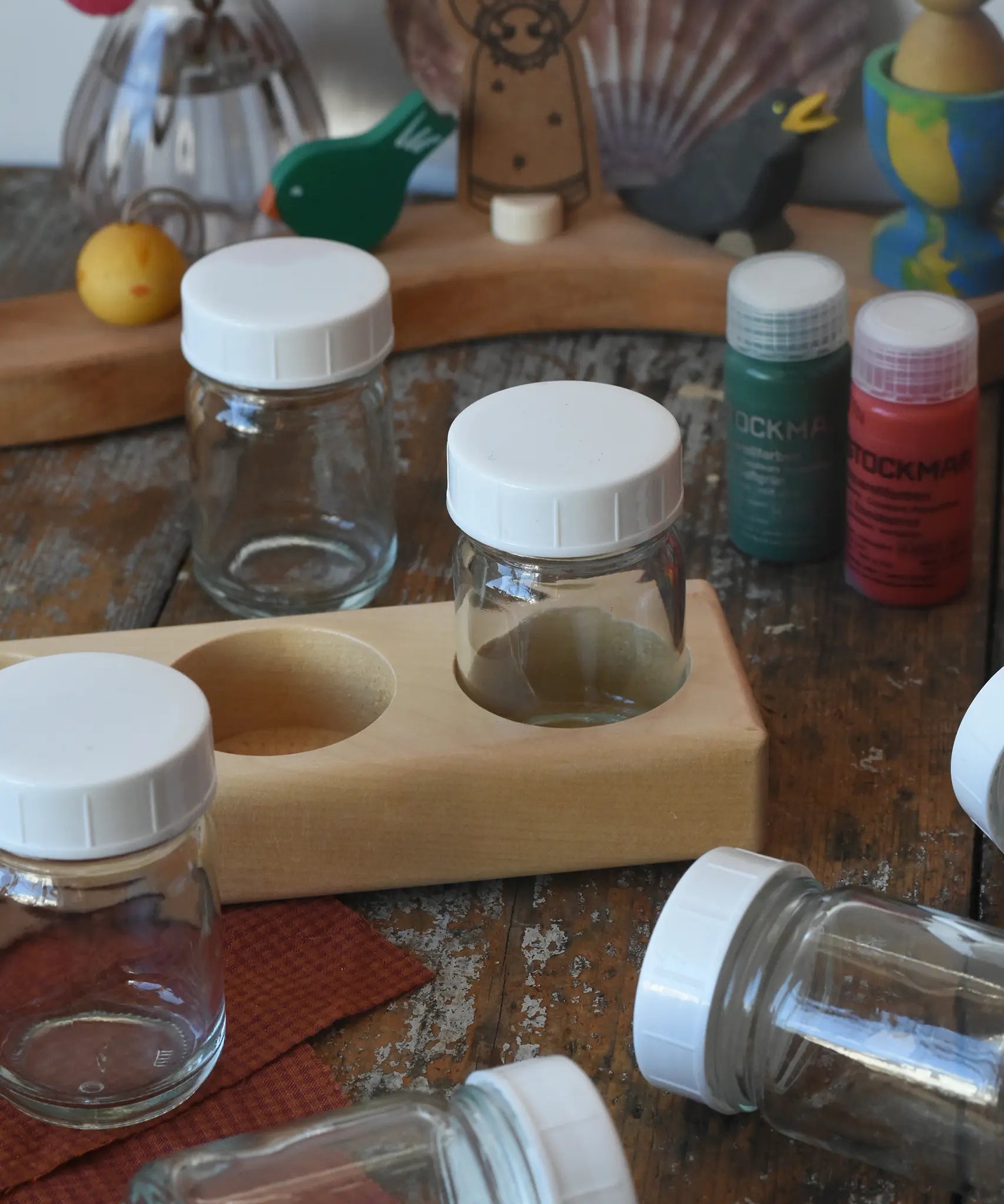 50ml Glass paint jar pots with lids show on a wooden holder block. 