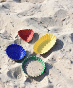 The Glückskäfer Metal Sand Moulds placed on sand, the green circle mould has been filled with sand.