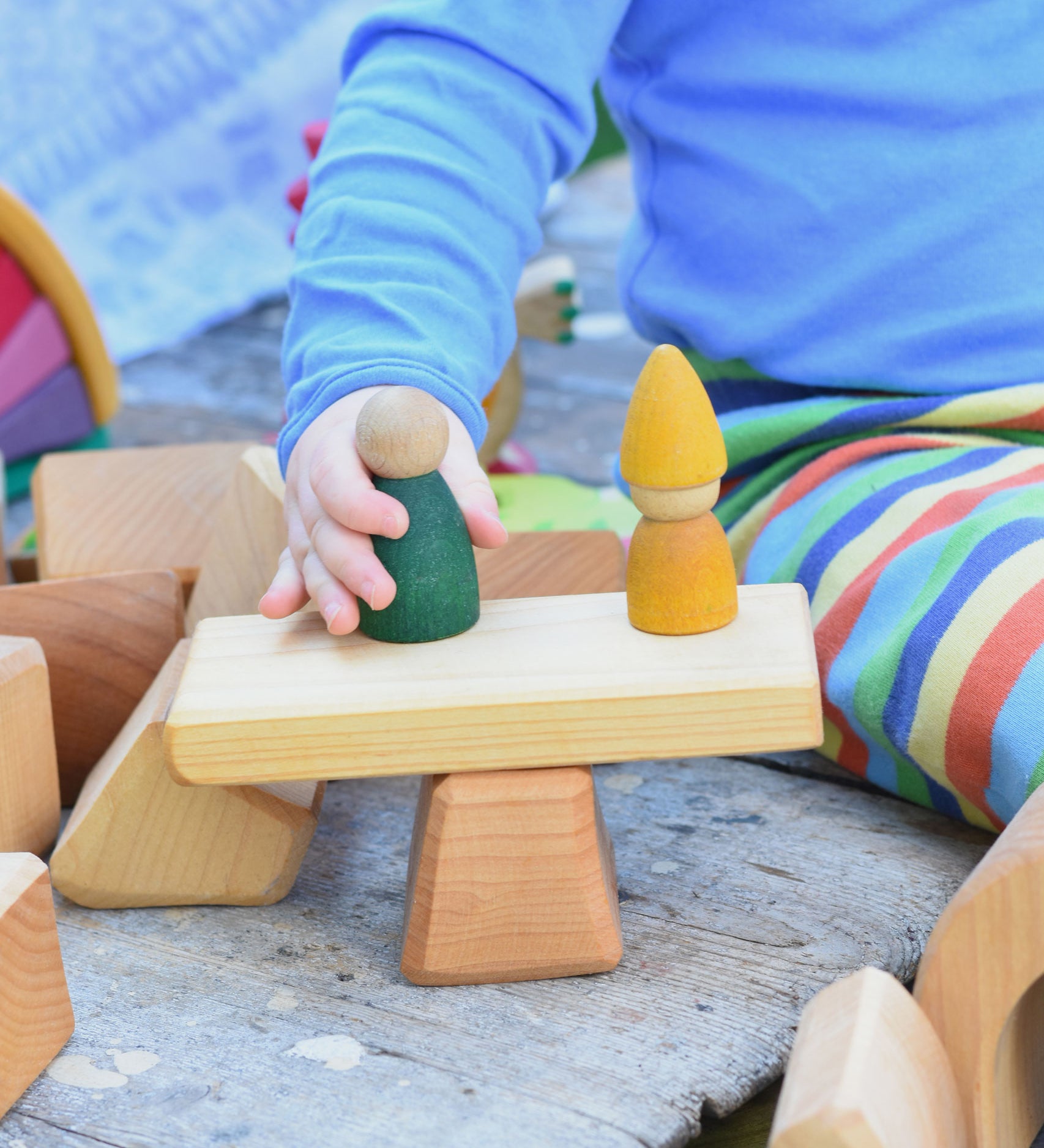 Two blocks from the Glückskäfer 17 Large Natural Blocks set used to create a pretend seesaw for wooden peg dolls. 