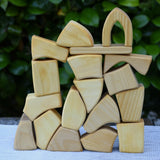 Glückskäfer 17 small natural blocks stacked up on a table outoors. 