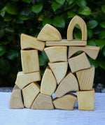 Glückskäfer 17 small natural blocks stacked up on a table outoors. 