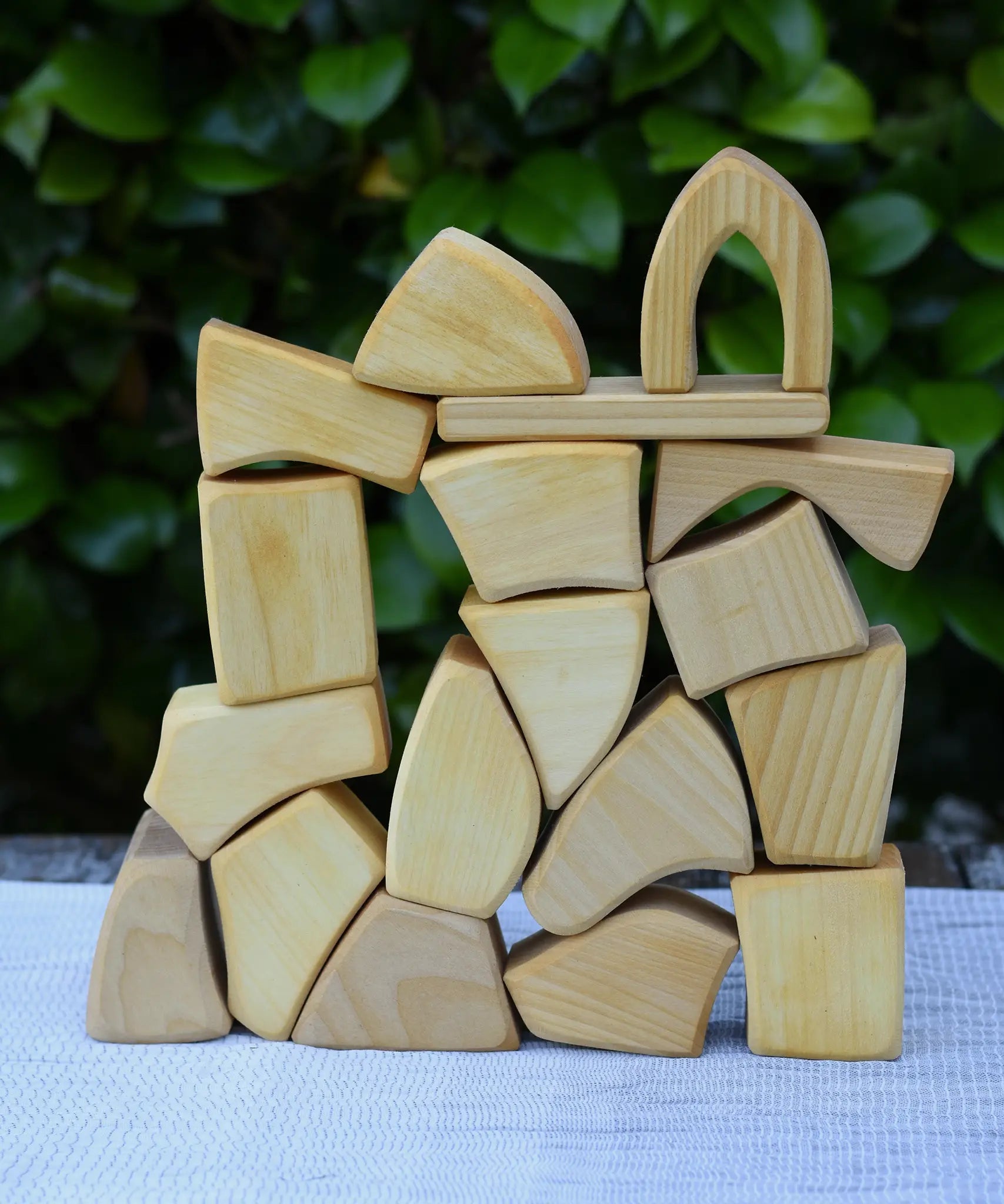 Glückskäfer 17 small natural blocks stacked up on a table outoors. 