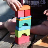 A close up of a child stacking wooden toy blocks on top of each other. The blocks are from the Glückskäfer 20-Piece Small Toscana Blocks Set. 
