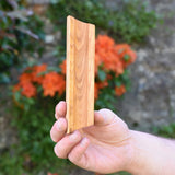 A piece of track from the Glückskäfer 23 Piece Wooden Marble Track held up in an adult's hand.