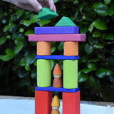 A child playing with the Glückskäfer 53 piece big provence wooden blocks set creating a tower with Grapat tomten nins placed inside.