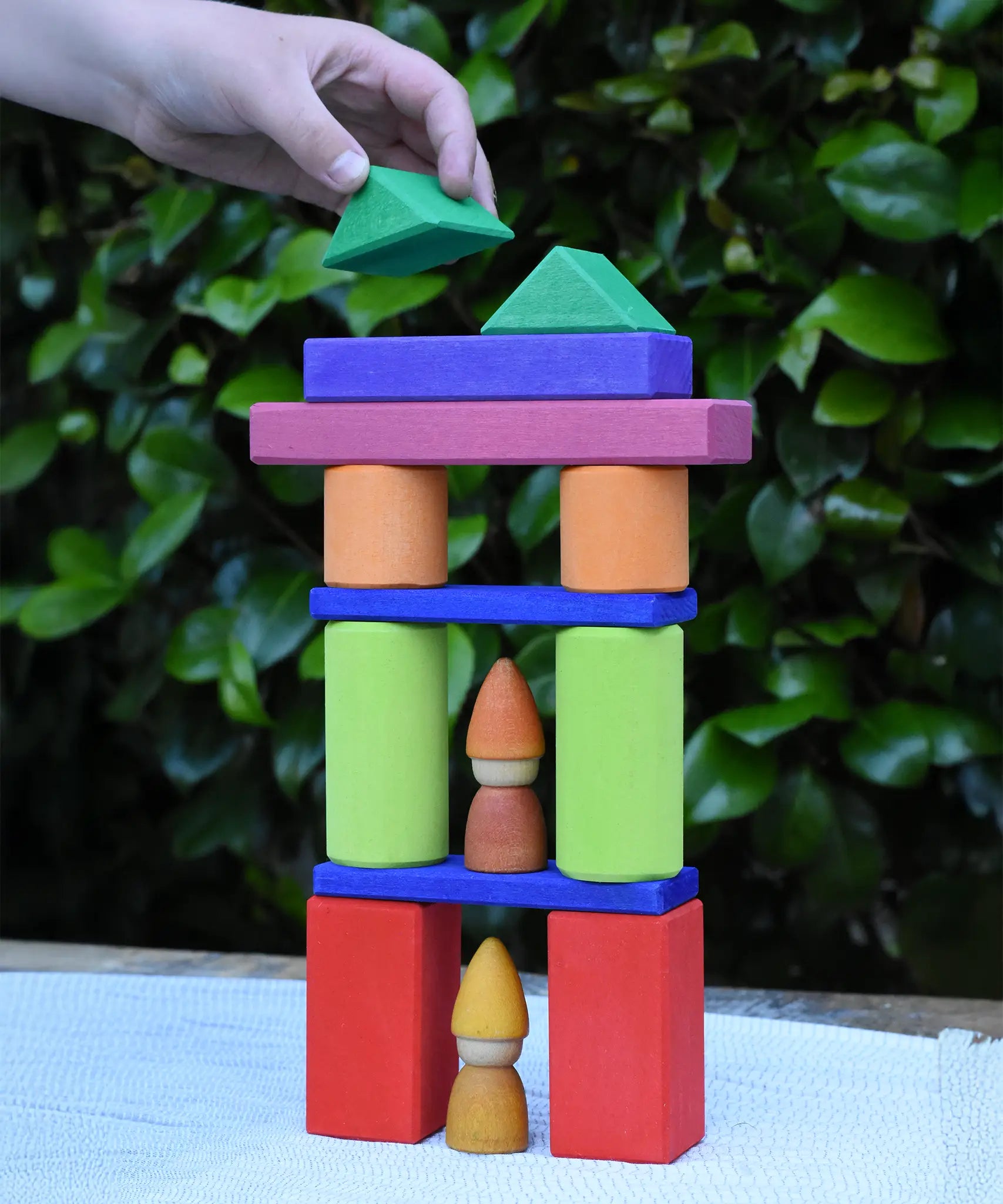 A child playing with the Glückskäfer 53 piece big provence wooden blocks set creating a tower with Grapat tomten nins placed inside.