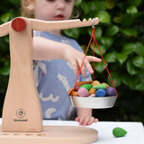 Child placing Grapat mandlaa pieces onto the Glückskäfer balance with weights children's weighing scales toy.  