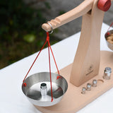 Glückskäfer balance with weights children's weighing scales toy. One side has one weight placed onto it.  
