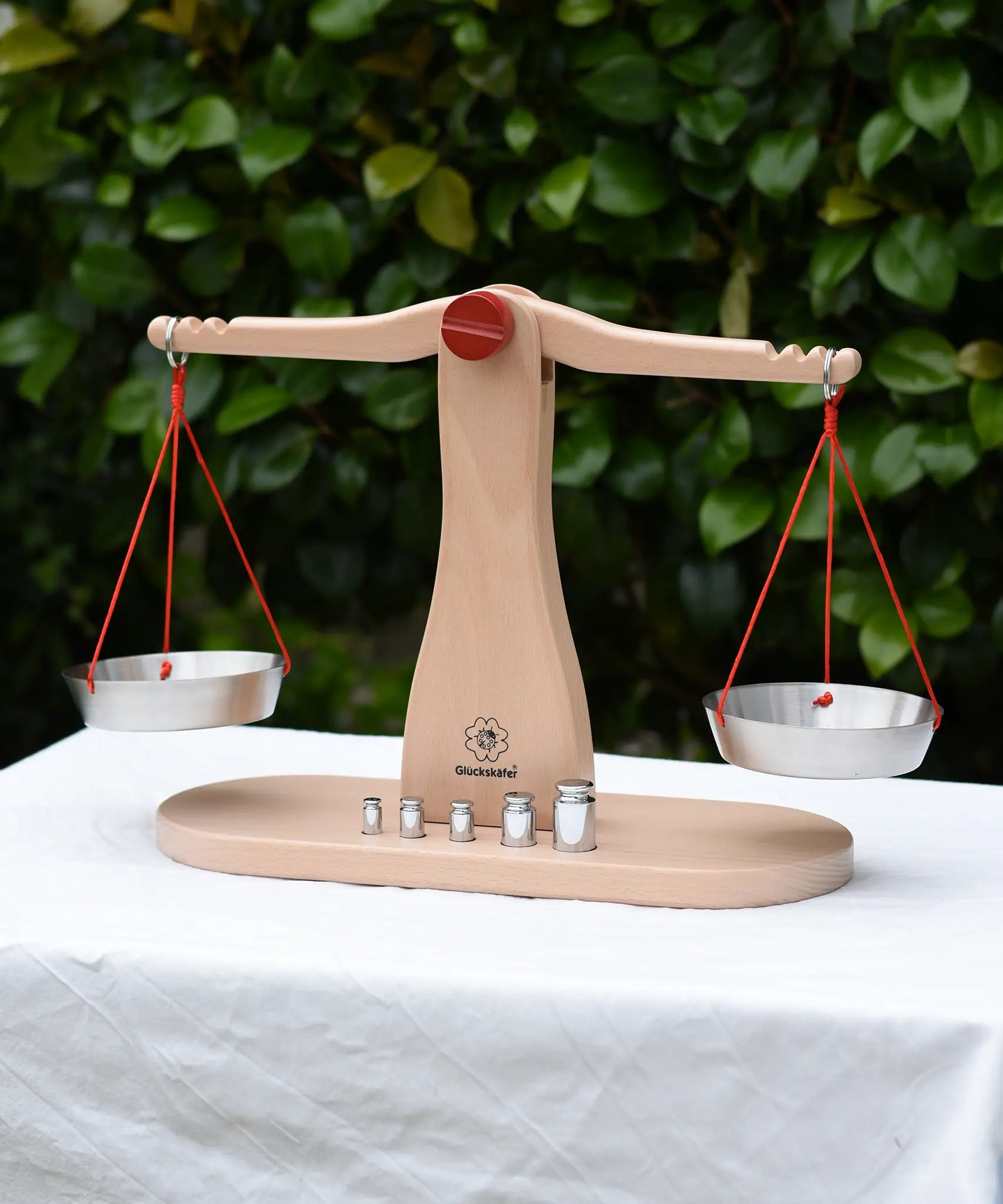 Glückskäfer balance with weights children's weighing scales toy placed on a table outdoors.  