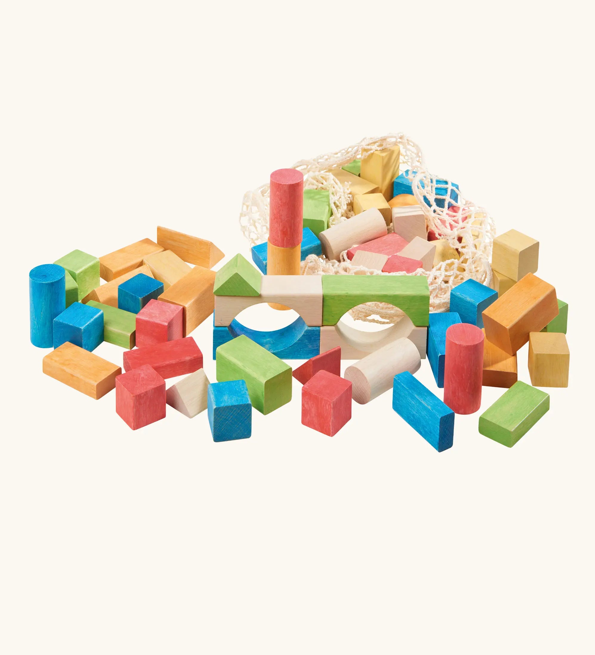 White mesh drawstring bag filled with Glückskäfer colorful wooden blocks next to a pile of wooden blocks. Glückskäfer Wooden Bio Geometric Building Blocks, 58 Piece Set.