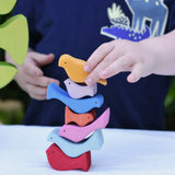 Child stacking the colourful wooden bird shaped pieces from the Glückskäfer light green wooden bird tree puzzle stacker toy on top of each other. 