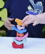 Child stacking the colourful wooden bird shaped pieces from the Glückskäfer light green wooden bird tree puzzle stacker toy on top of each other. 