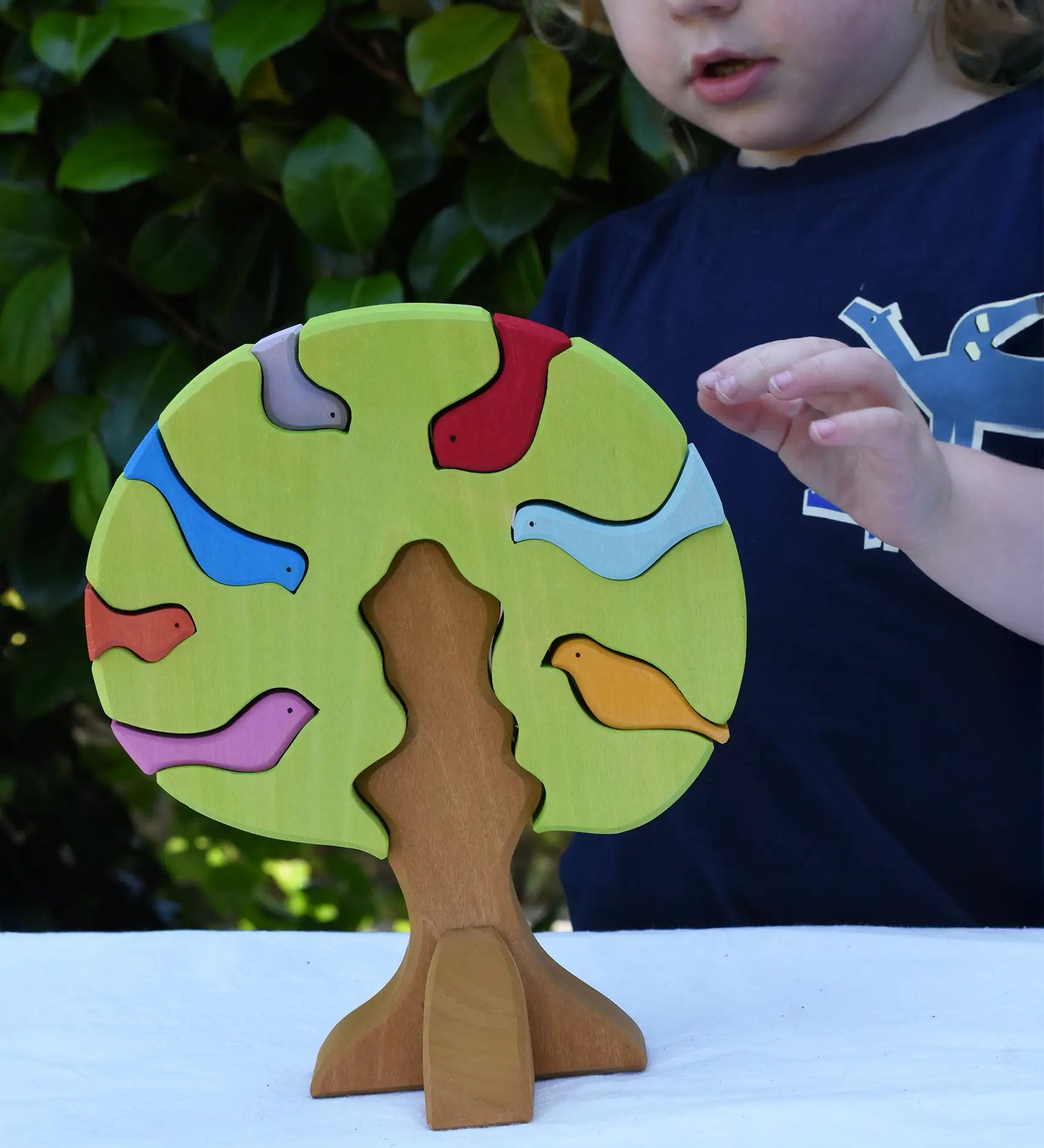 Glückskäfer light green wooden bird tree puzzle stacker toy, a child is reaching for the tree.