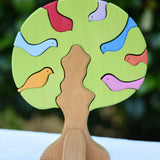 Glückskäfer light green wooden bird tree puzzle stacker toy placed on a table outdoors.
