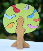 Glückskäfer light green wooden bird tree puzzle stacker toy placed on a table outdoors.