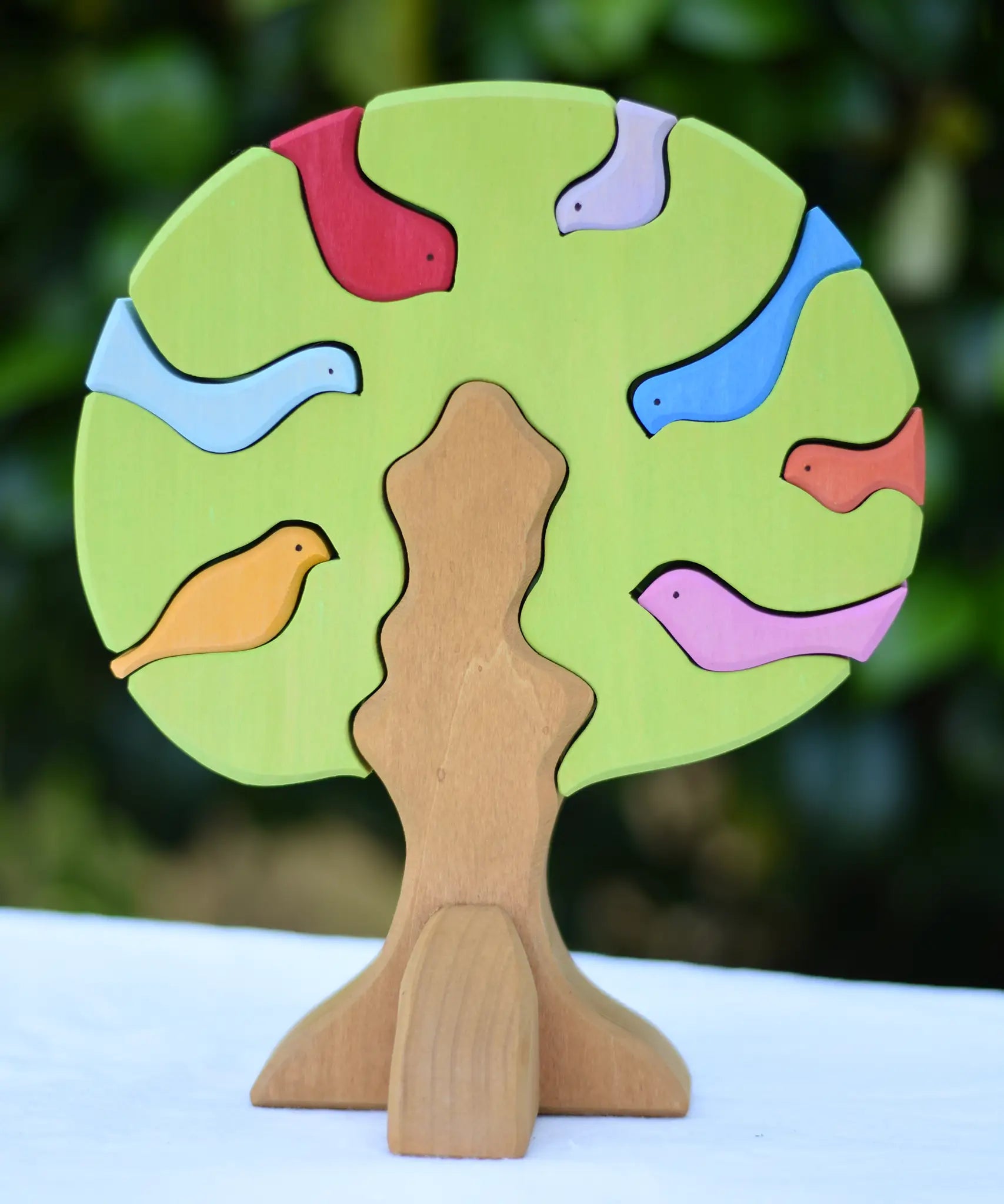 Glückskäfer light green wooden bird tree puzzle stacker toy placed on a table outdoors.