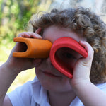A child holding up two of the arch pieces from the Gluckskafer castle over their eyes, using them as a pair of binoculars. 