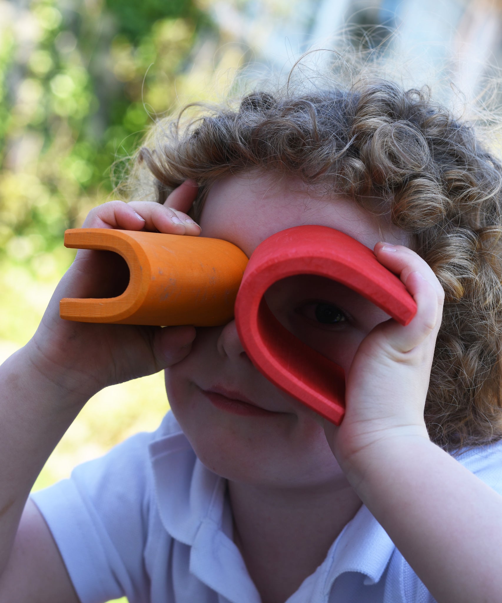 A child holding up two of the arch pieces from the Gluckskafer castle over their eyes, using them as a pair of binoculars. 