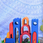 The pieces from the Gluckskafer castle stacked on the green coloured base piece. There are wooden bird figures laced underneath the arches. 