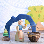 The largest arch from the Glückskäfer Blue Grotto shown in a small world play scene with an Ostheimer female farmwr figure standing next to a Kraul basket with an Ostheimer bird in it. 