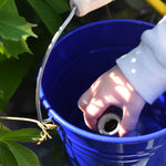 A close up of a child's hand placing a seedbom container into Glückskäfer Blue Metal Bucket.