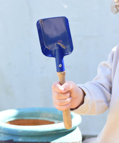 A child holding a Glückskäfer Square Metal Blue Shovel in their hand.