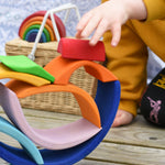 A close up of a child's hand placing a piece of the Glückskäfer Blue Sunrise Set on a stack.