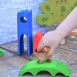 A child's hand placing a Bumbu Capybara on the green coloured bridge piece from the Gluckskafer Castle set. 