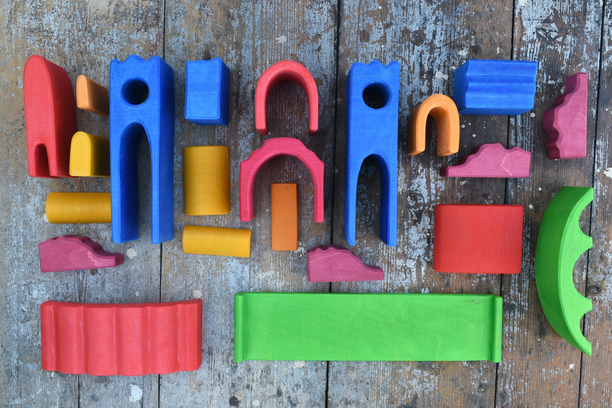 The pieces from the Gluckskafer blue wooden castle set laid out on a wooden surface. 