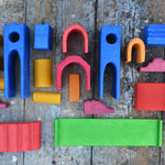 The pieces from the Gluckskafer blue wooden castle set laid out on a wooden surface. 