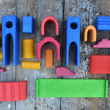 The pieces from the Gluckskafer blue wooden castle set laid out on a wooden surface. 