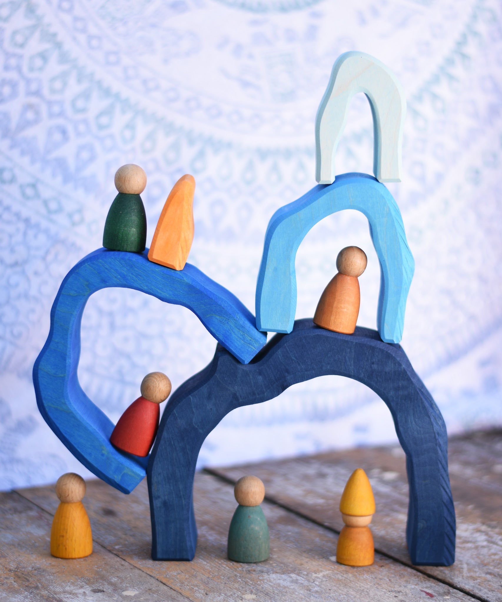 The arches from the Glückskäfer Blue Grotto set tacked on top of each other with Graapt wooden Nin peg dolls placed on and underneath the stack.