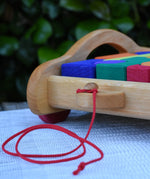 Close up of red pull along string on the front of the Gluckskafer carriage wooden toy block set. 