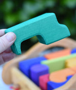 The largest block from the Gluckskafer carriage wooden toy block set in an adult's hand.