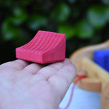 The smallest block from the Gluckskafer carriage wooden toy block set in an adult's hand.