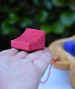 The smallest block from the Gluckskafer carriage wooden toy block set in an adult's hand.