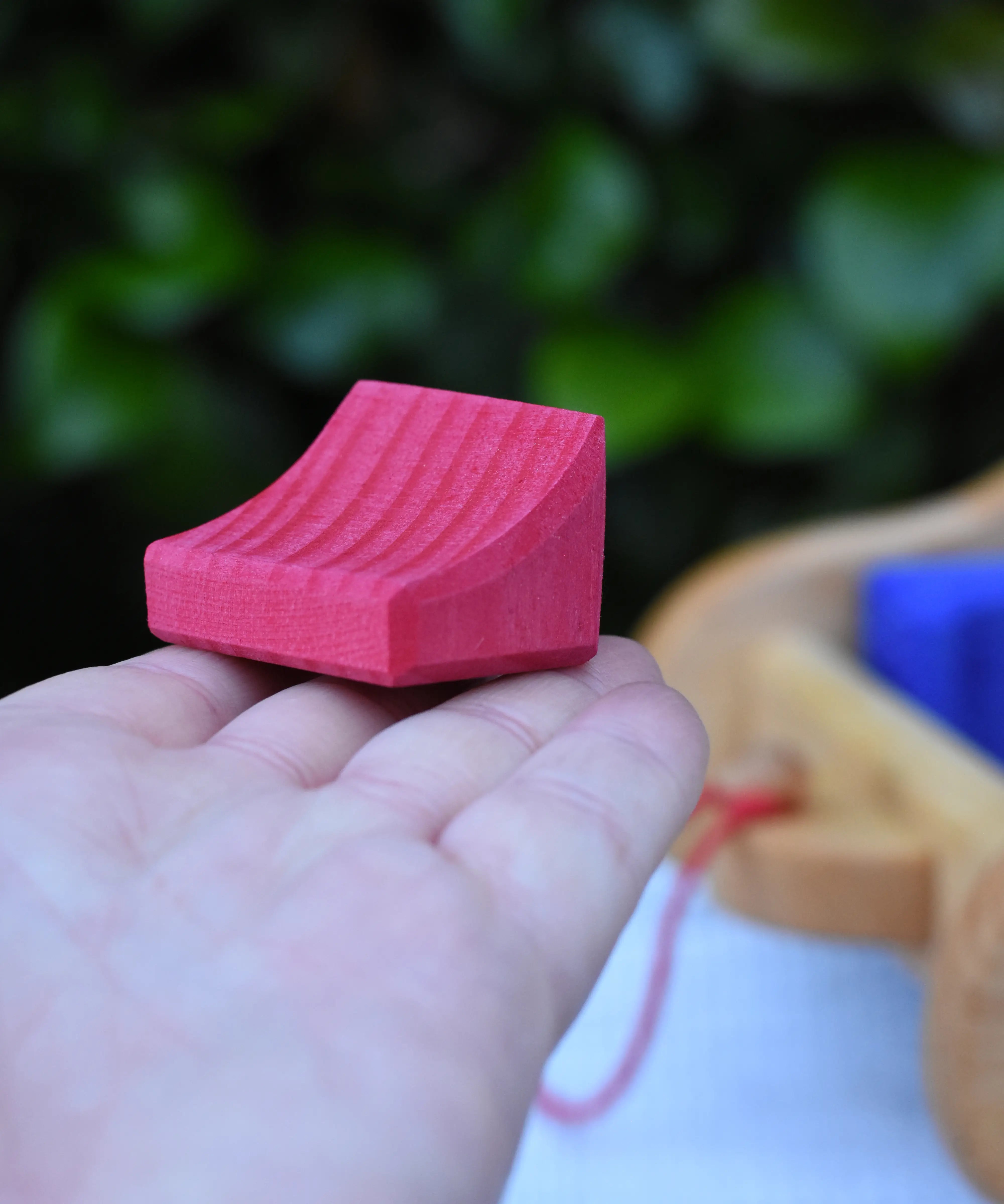 The smallest block from the Gluckskafer carriage wooden toy block set in an adult's hand.