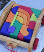 Gluckskafer carriage wooden toy block set. A natural wood pull along car with 17 colourful blocks. Close up of blocks.