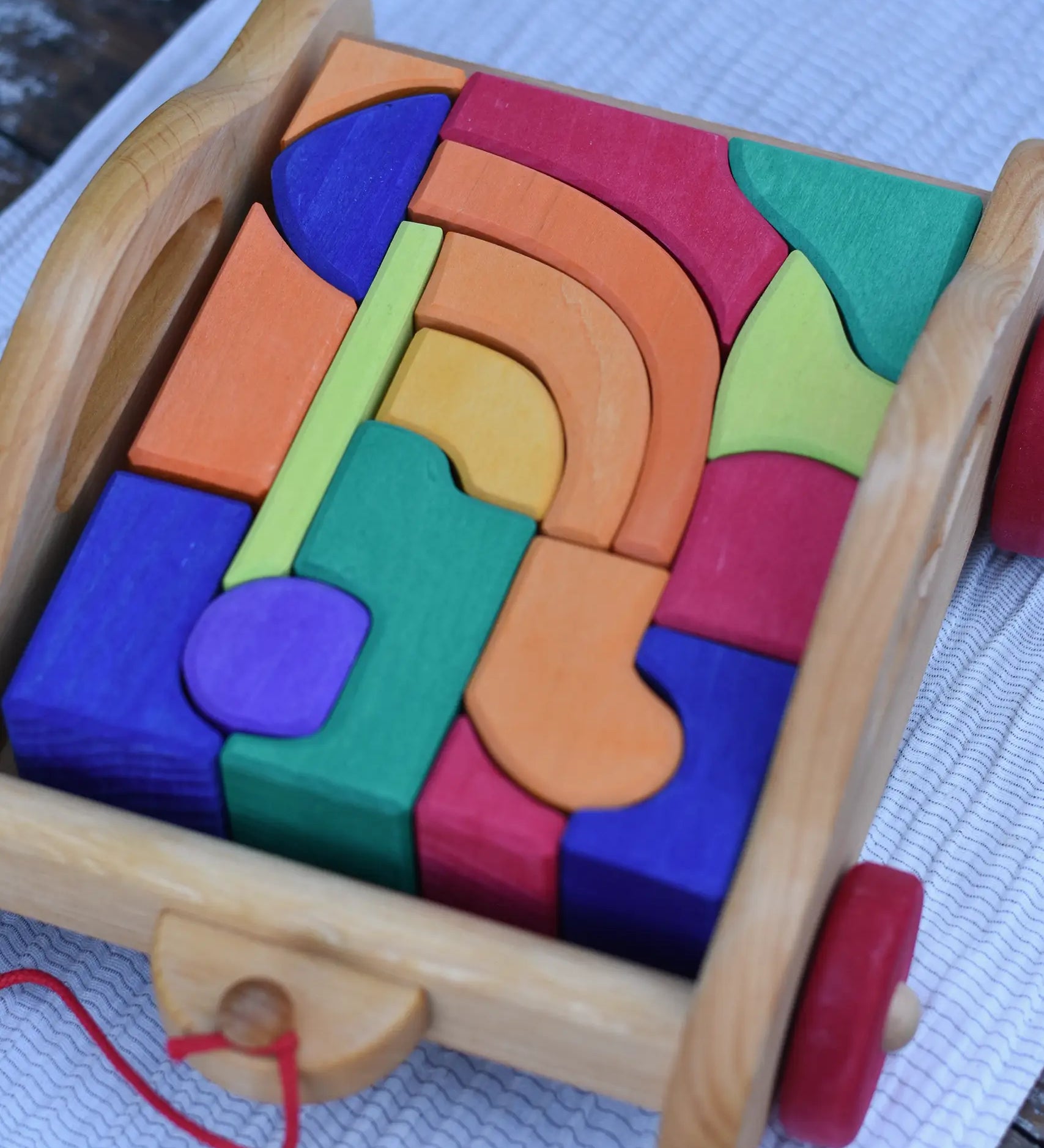 Gluckskafer carriage wooden toy block set. A natural wood pull along car with 17 colourful blocks. Close up of blocks.