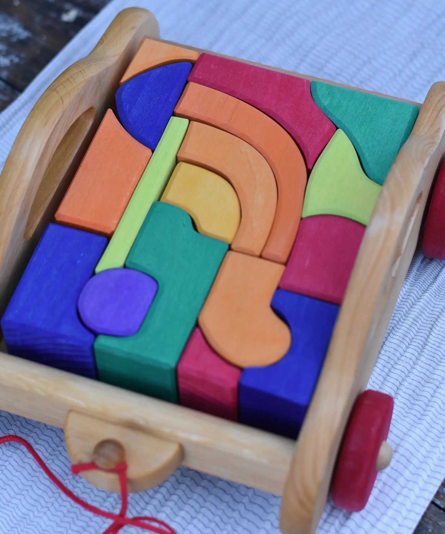 Gluckskafer carriage wooden toy block set. A natural wood pull along car with 17 colourful blocks. Close up of blocks.
