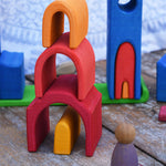 The house shaped piueces from the Gluckskafer castle stacked up on top of each other to create a tower. A Grapat Nin peg doll can be seen standing at the side of the stack. 